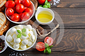 Italian food ingredients Ã¢â¬â mozzarella, tomatoes, basil and olive oil on rustic wooden table.